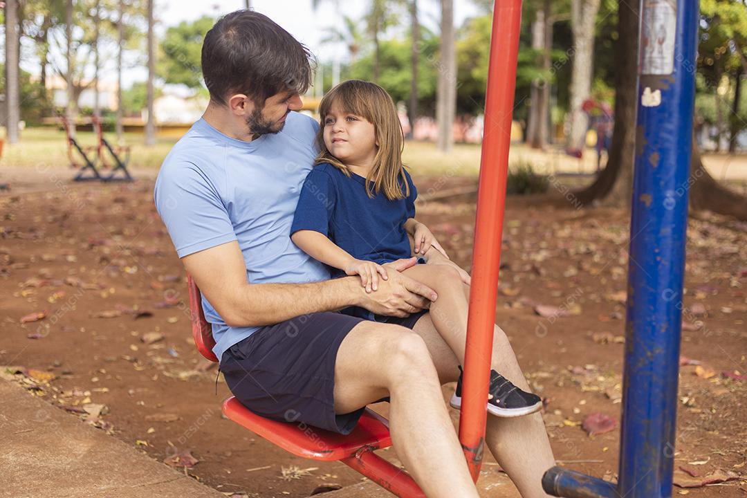 pai e filho fazendo exercício em aparelhos ao ar livre com a filha.
