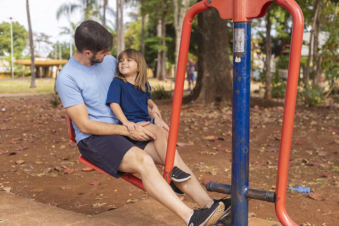 pai e filho fazendo exercício em aparelhos ao ar livre com a filha.