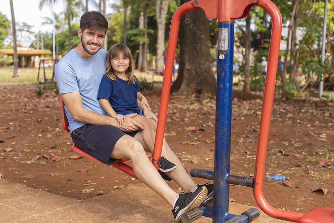 pai e filho fazendo exercício em aparelhos ao ar livre com a filha.