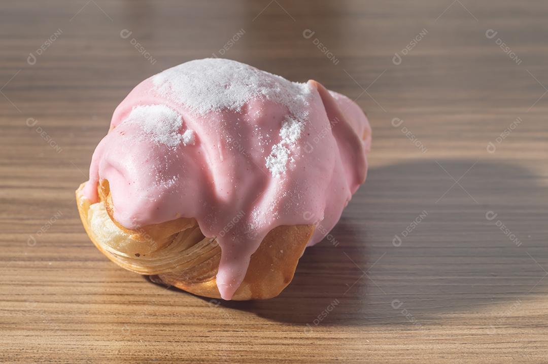 Croissant com cobertura de morango e recheio de doce de leite.