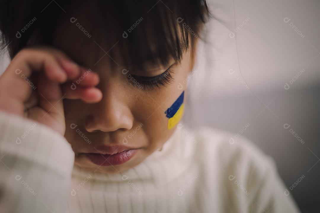 Uma criança com a bandeira da Ucrânia está chorando. Tristeza saudade esperança