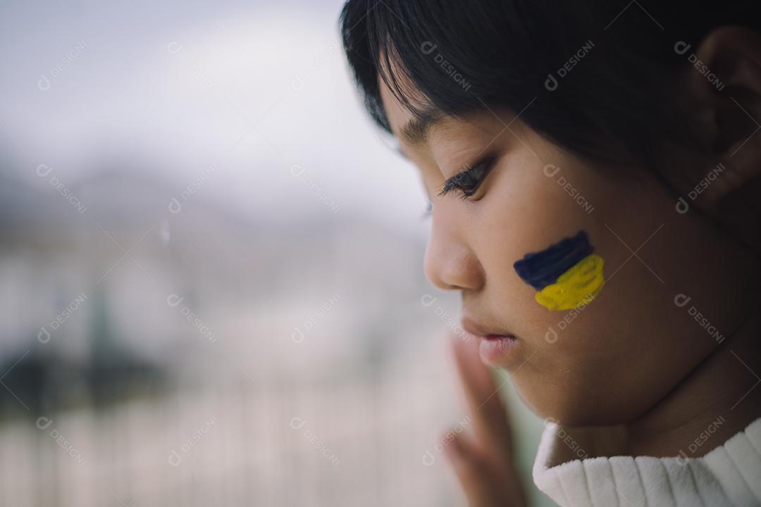 Uma criança com a bandeira da Ucrânia está chorando. Tristeza saudade esperança