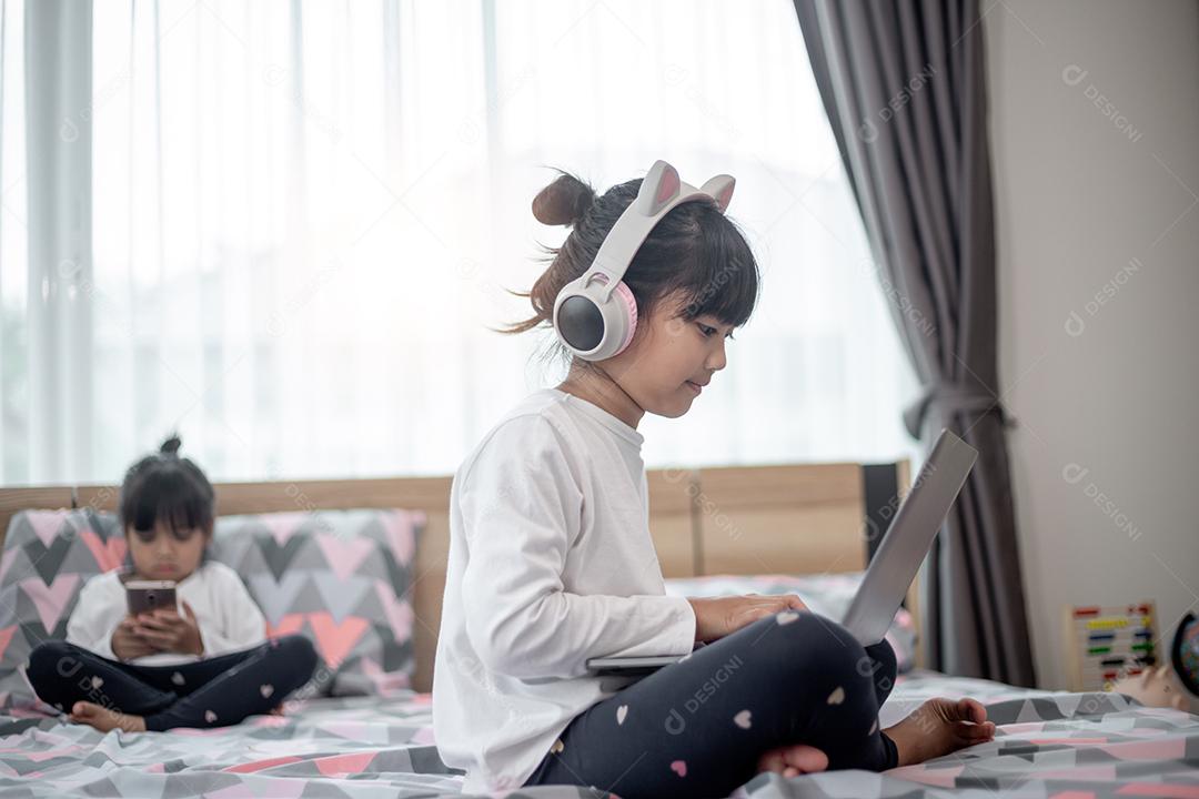 Menina asiática usando um laptop enquanto estava deitado na cama