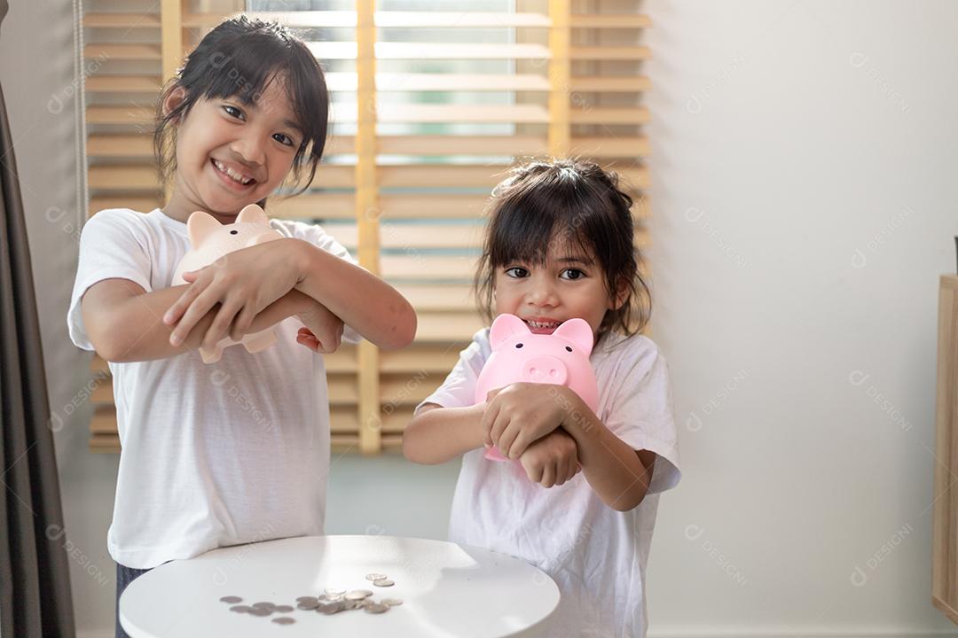 Menina asiática economizando dinheiro em um cofrinho, aprendendo sobre s