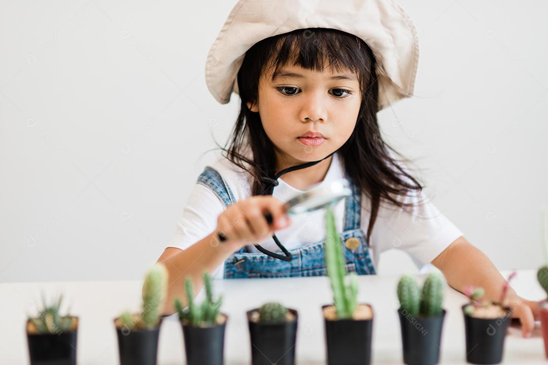 A garotinha asiática está plantando plantas na casa, conceito de pl