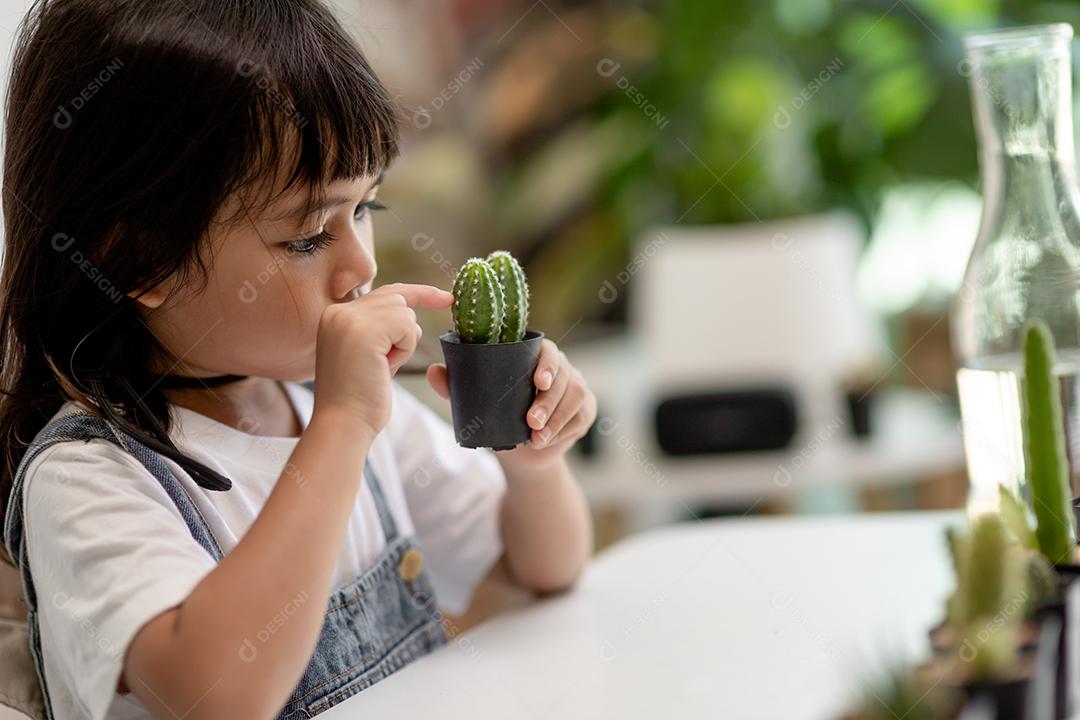 A garotinha asiática está plantando plantas na casa, conceito de pl
