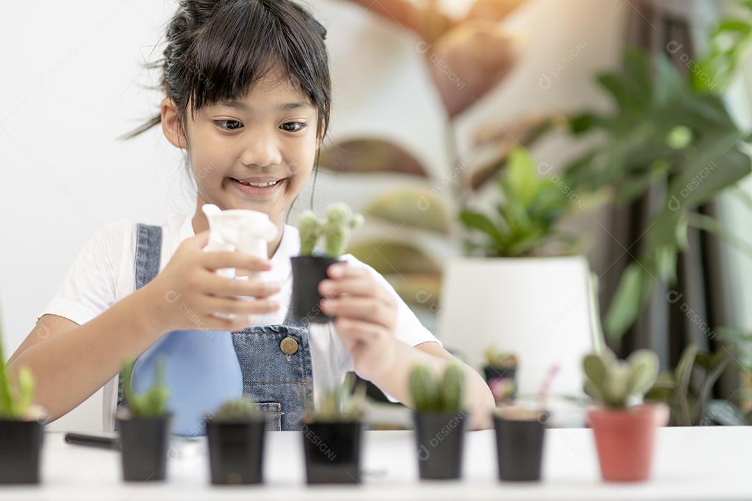 A garotinha asiática está plantando plantas na casa, conceito de pl