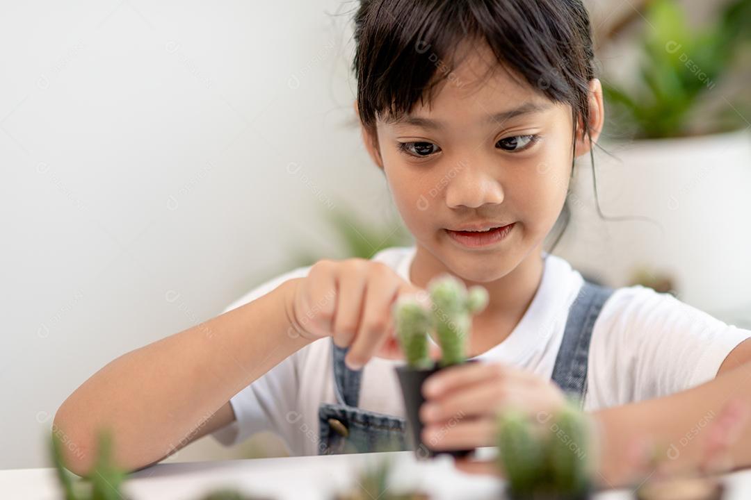 A garotinha asiática está plantando plantas na casa, conceito de pl