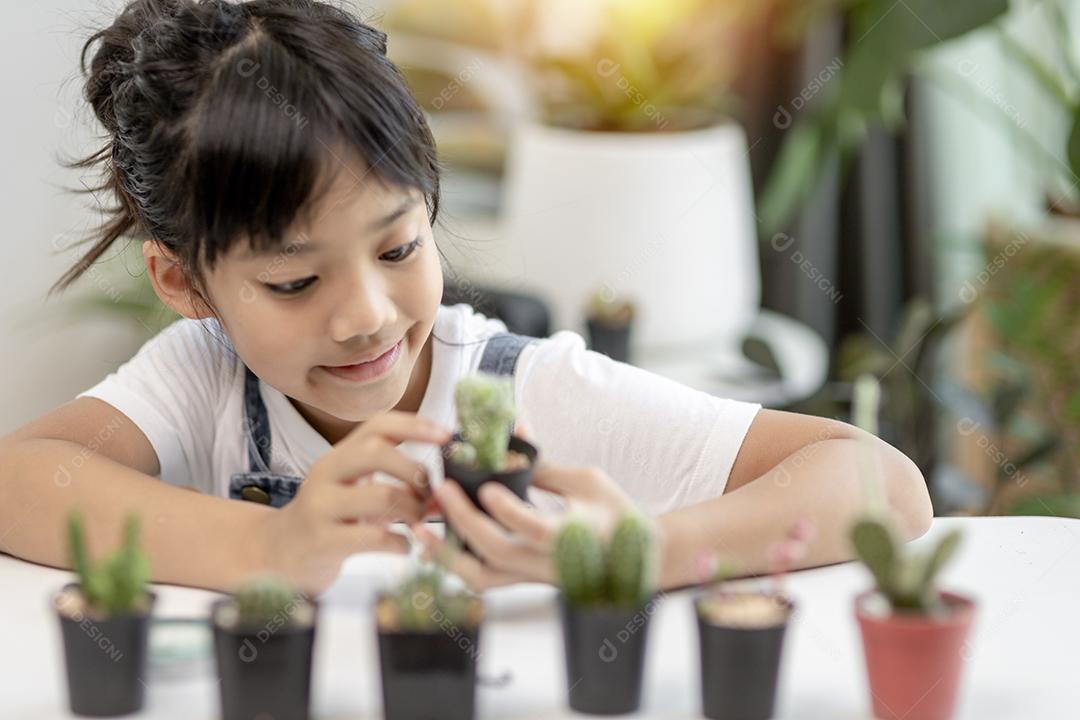 A garotinha asiática está plantando plantas na casa, conceito de pl