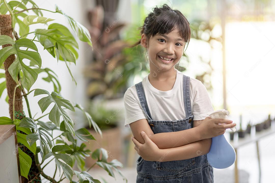 A garotinha asiática está plantando plantas na casa, conceito de pl