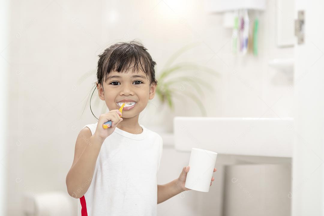 Menina bonitinha limpando os dentes com uma escova de dentes no th