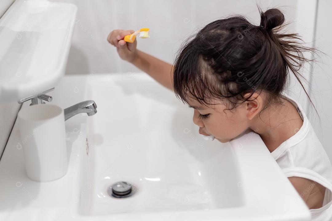 Menina bonitinha limpando os dentes com uma escova de dentes no th