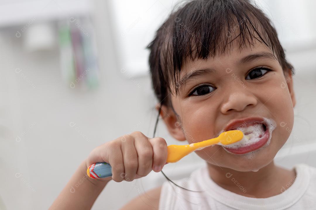 Menina bonitinha limpando os dentes com uma escova de dentes no th