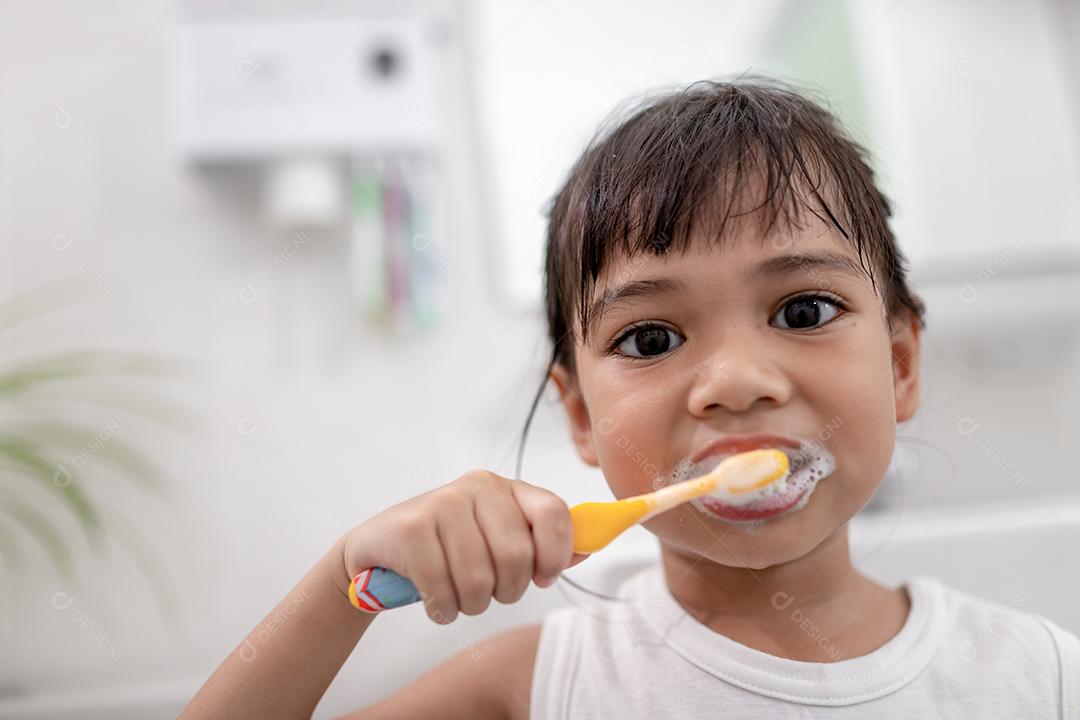 Menina bonitinha limpando os dentes com uma escova de dentes no th