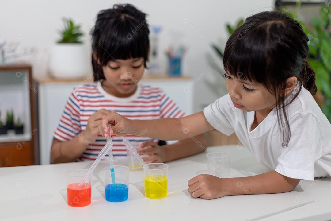 Crianças asiáticas assistem com entusiasmo aos experimentos de química.