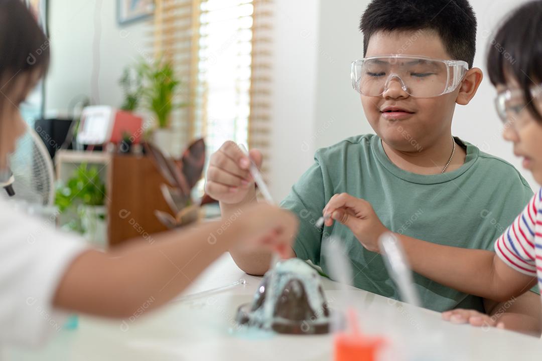 Crianças repetindo e observando um projeto de laboratório de ciências em casa - o vulcão de bicarbonato de sódio e vinagre