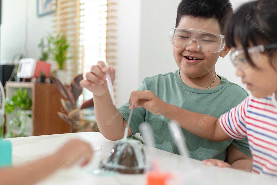 Crianças repetindo e observando um projeto de laboratório de ciências em casa - o vulcão de bicarbonato de sódio e vinagre