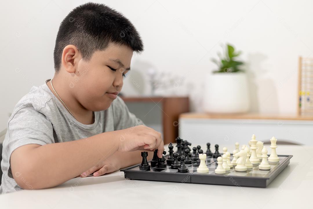Menino e menina estão jogando xadrez em casa. Crianças jogando xadrez