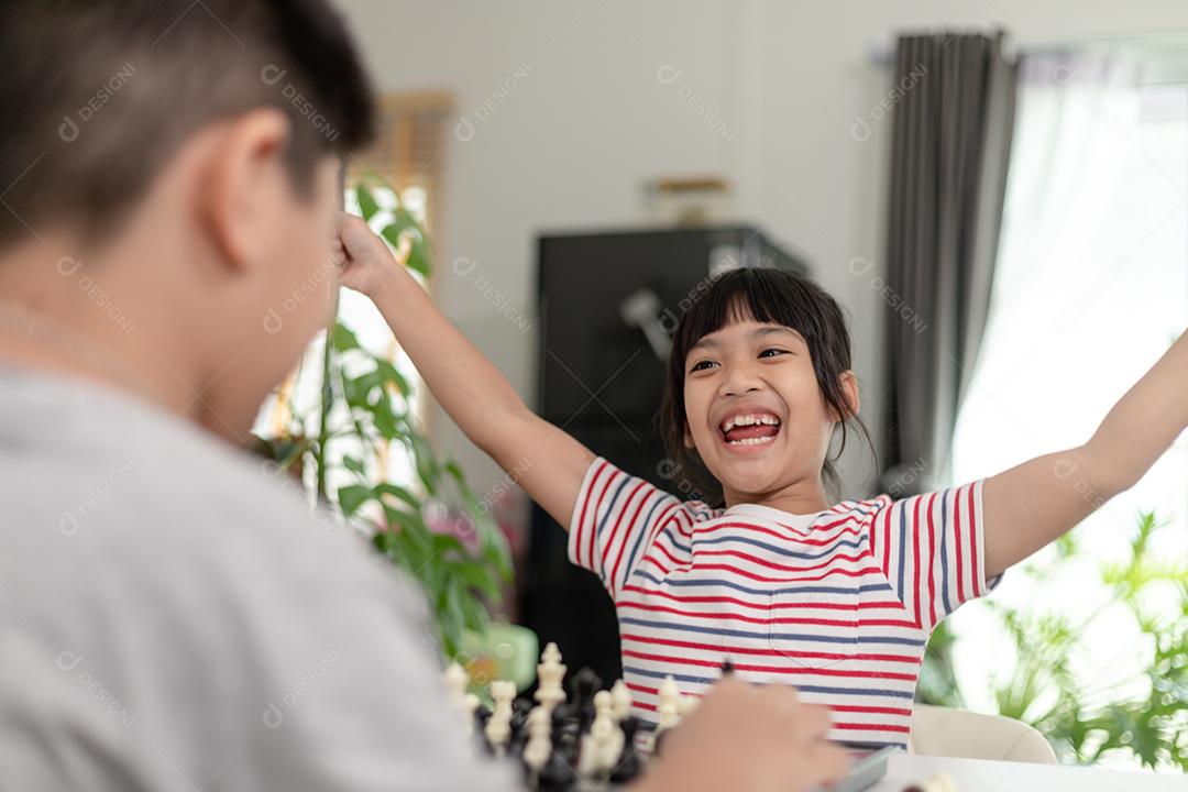 Menino e menina estão jogando xadrez em casa. Crianças jogando xadrez