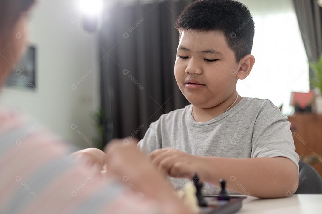 Menino e menina estão jogando xadrez em casa. Crianças jogando xadrez