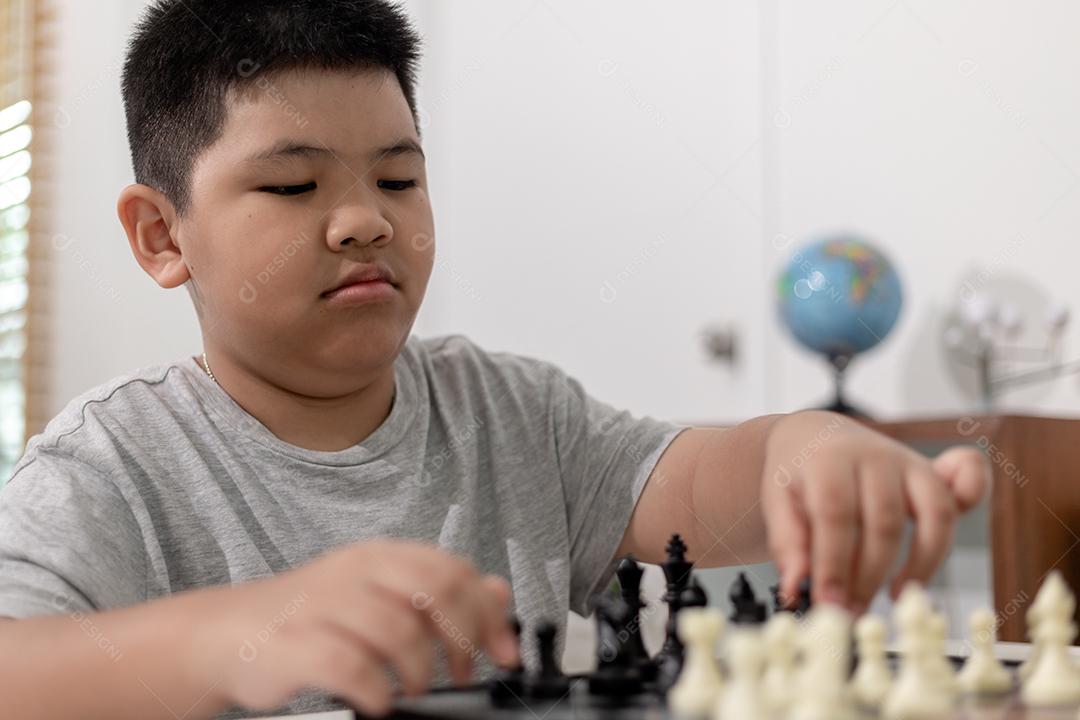 Menino e menina estão jogando xadrez em casa. Crianças jogando xadrez