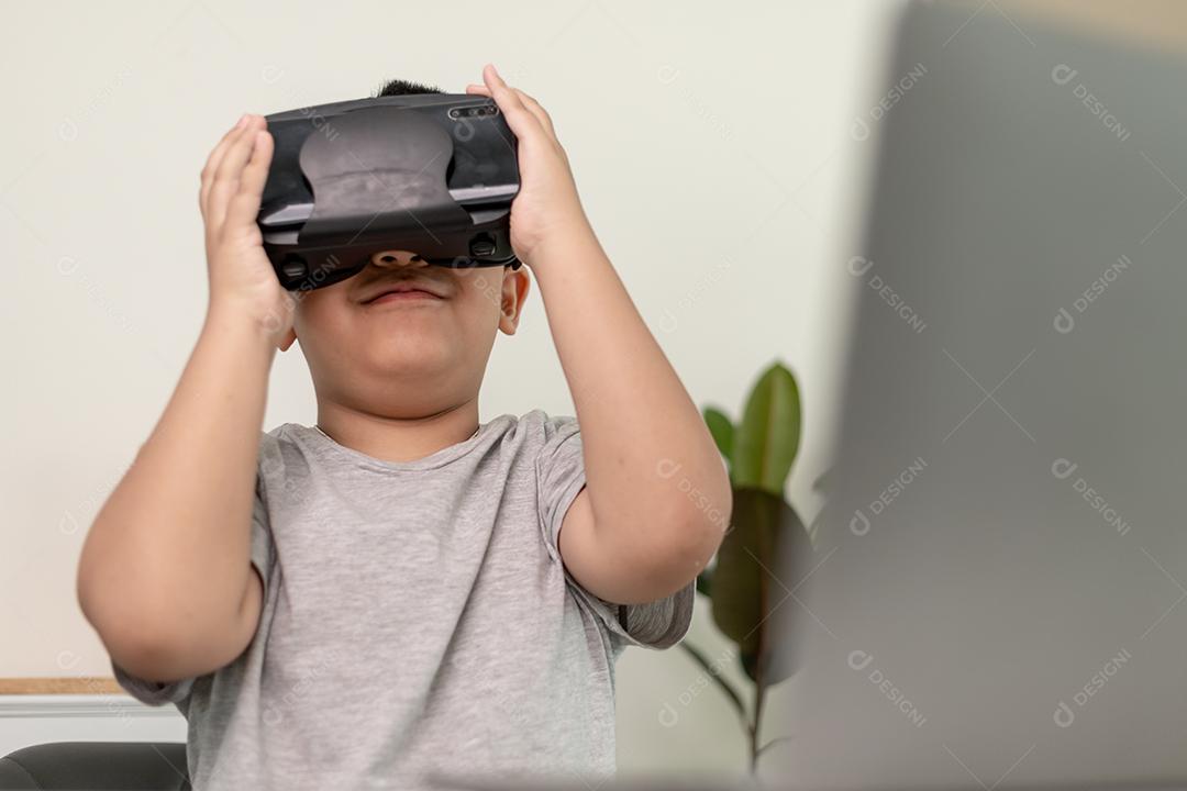 Menino asiático com óculos VR estudando ciências em casa, estudante curioso usa um fone de ouvido de realidade virtual para estudar ciência em casa estudo online estilo de vida futurista aprendizagem