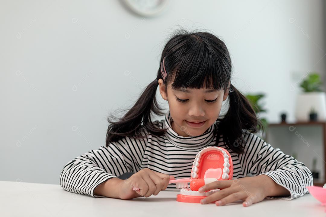 Uma criança pequena brinca com mandíbulas artificiais. Odontologia infantil.