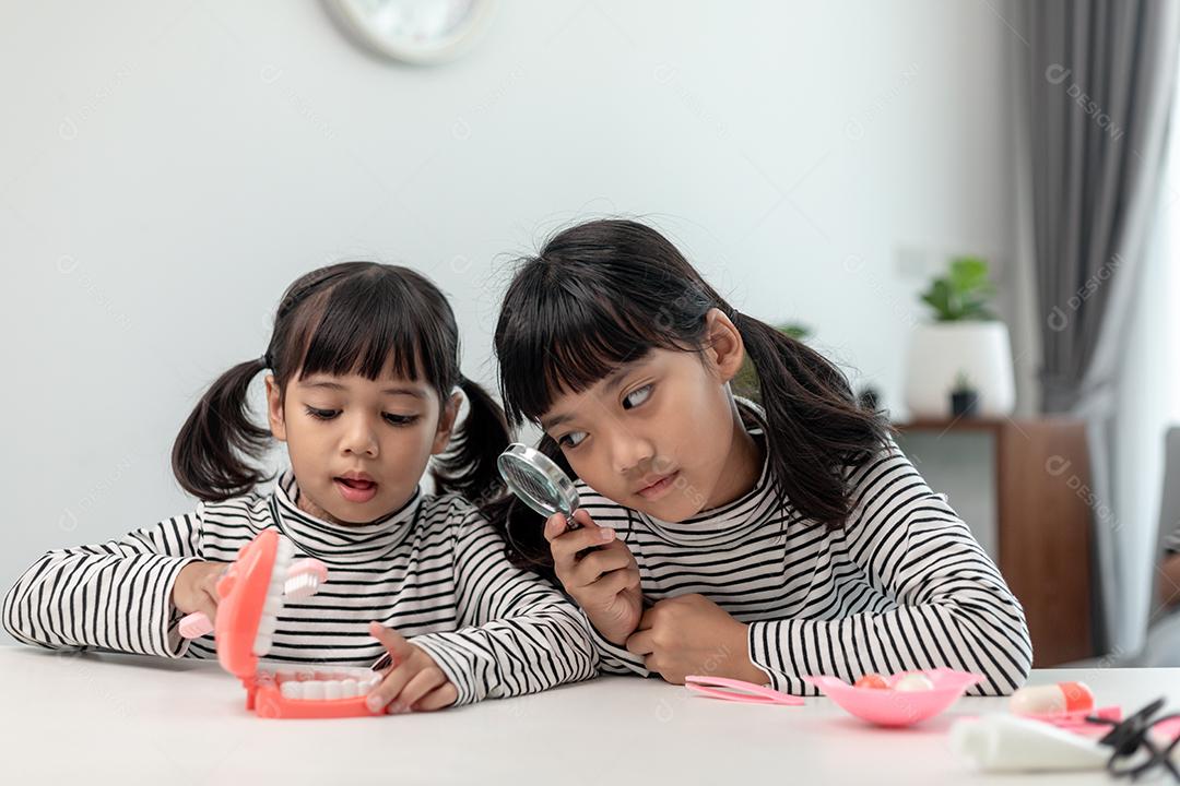 Garotinha asiática aprendendo aula online em casa com a mãe. A criança pré-escolar usa o laptop para fazer a lição de casa, o ensino em casa do professor da escola pela internet remota digital com o apoio da mãe.