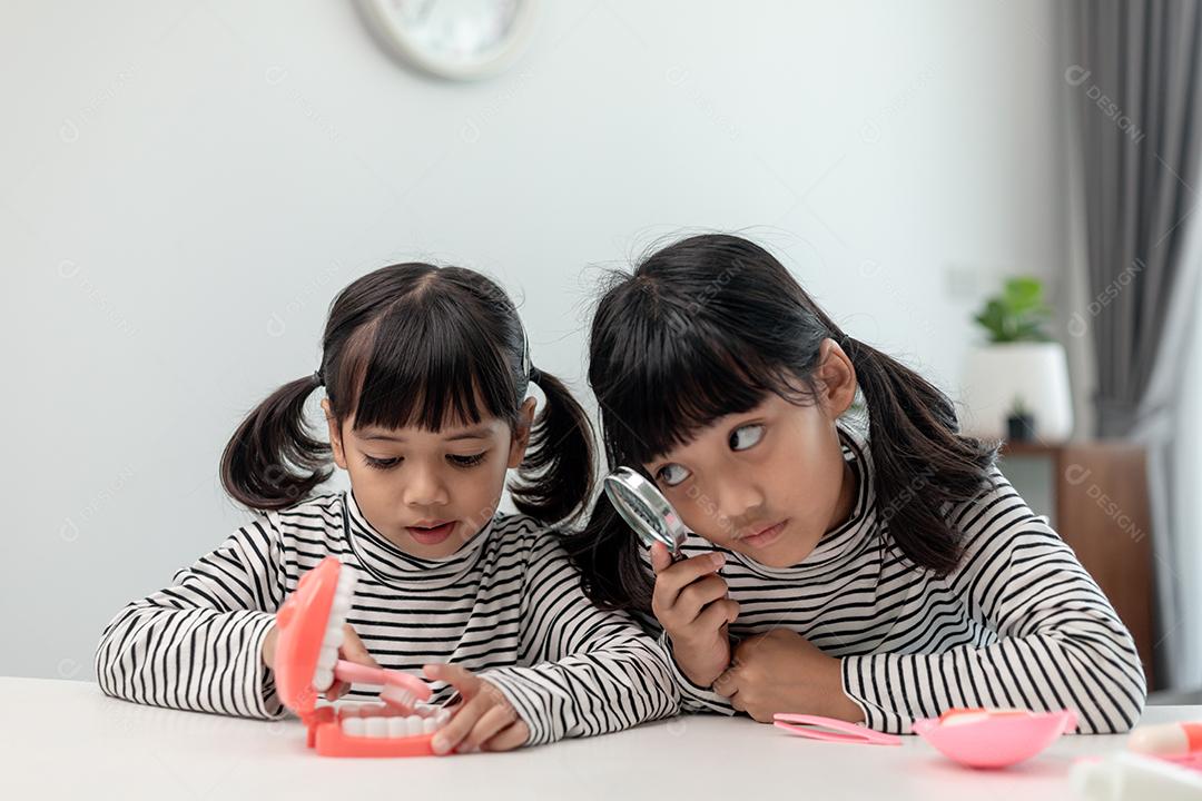 Garotinha asiática aprendendo aula online em casa com a mãe. A criança pré-escolar usa o laptop para fazer a lição de casa, o ensino em casa do professor da escola pela internet remota digital com o apoio da mãe.