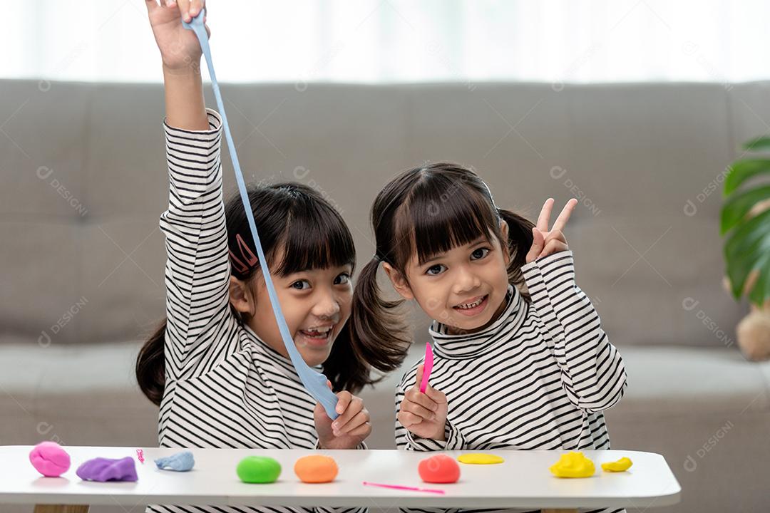 Crianças asiáticas brincam com formas de moldagem de argila, aprendendo brincando