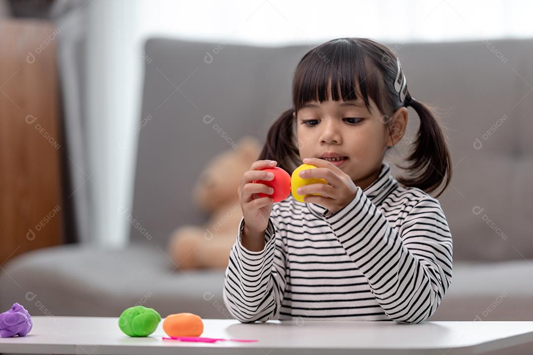 Crianças asiáticas brincam com formas de moldagem de argila, aprendendo brincando