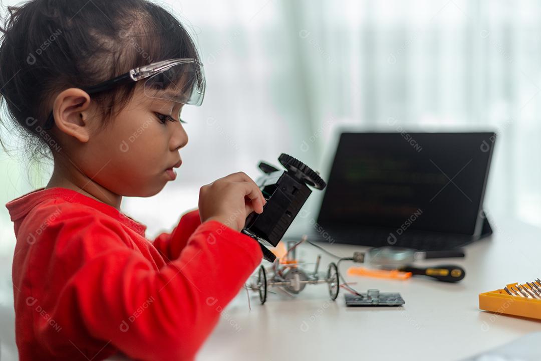 Os alunos da Ásia aprendem em casa na codificação de carros robóticos e cabos de placas eletrônicas em STEM, STEAM, código de computador de tecnologia de ciência de engenharia matemática em robótica para o conceito de crianças.