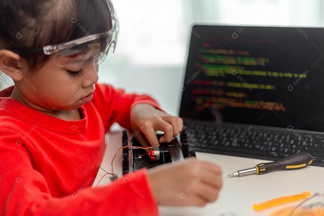 Os alunos da Ásia aprendem em casa na codificação de carros robóticos e cabos de placas eletrônicas em STEM, STEAM, código de computador de tecnologia de ciência de engenharia matemática em robótica para o conceito de crianças.