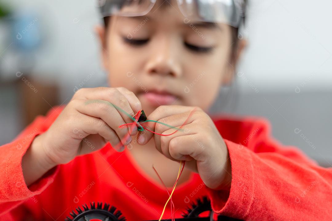 Os alunos da Ásia aprendem em casa na codificação de carros robóticos e cabos de placas eletrônicas em STEM, STEAM, código de computador de tecnologia de ciência de engenharia matemática em robótica para o conceito de crianças.