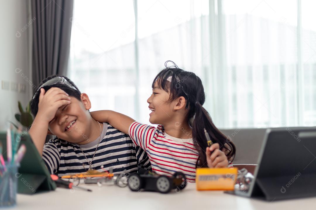 duas crianças asiáticas se divertindo aprendendo codificação juntas, aprendendo remotamente em casa, ciência STEM, educação escolar em casa, distanciamento social divertido, isolamento, novo conceito normal