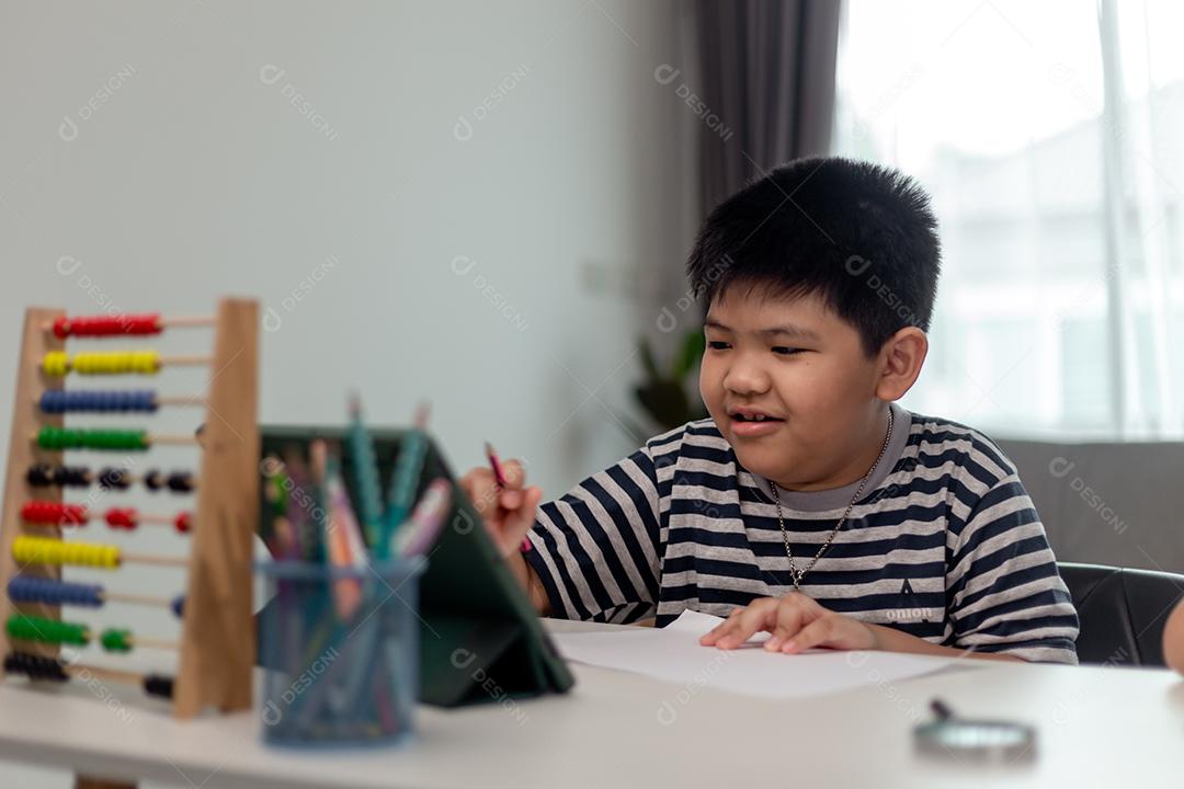Bonita criança asiática aprendendo aula on-line com videochamada do tablet em casa Conceito de distanciamento social