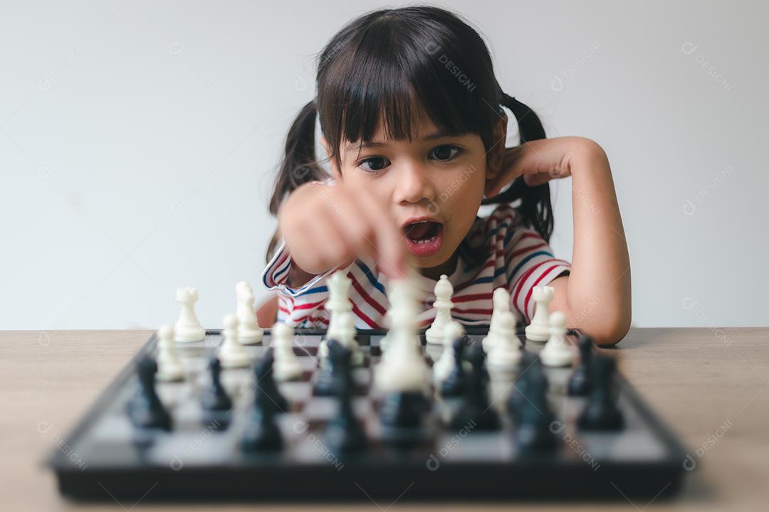 Menina asiática jogando xadrez em casa. um jogo de xadrez