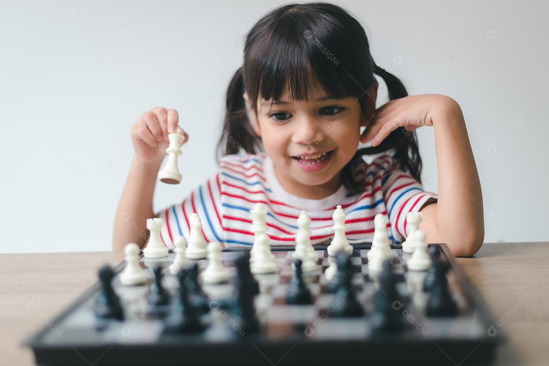 Menina asiática jogando xadrez em casa. um jogo de xadrez