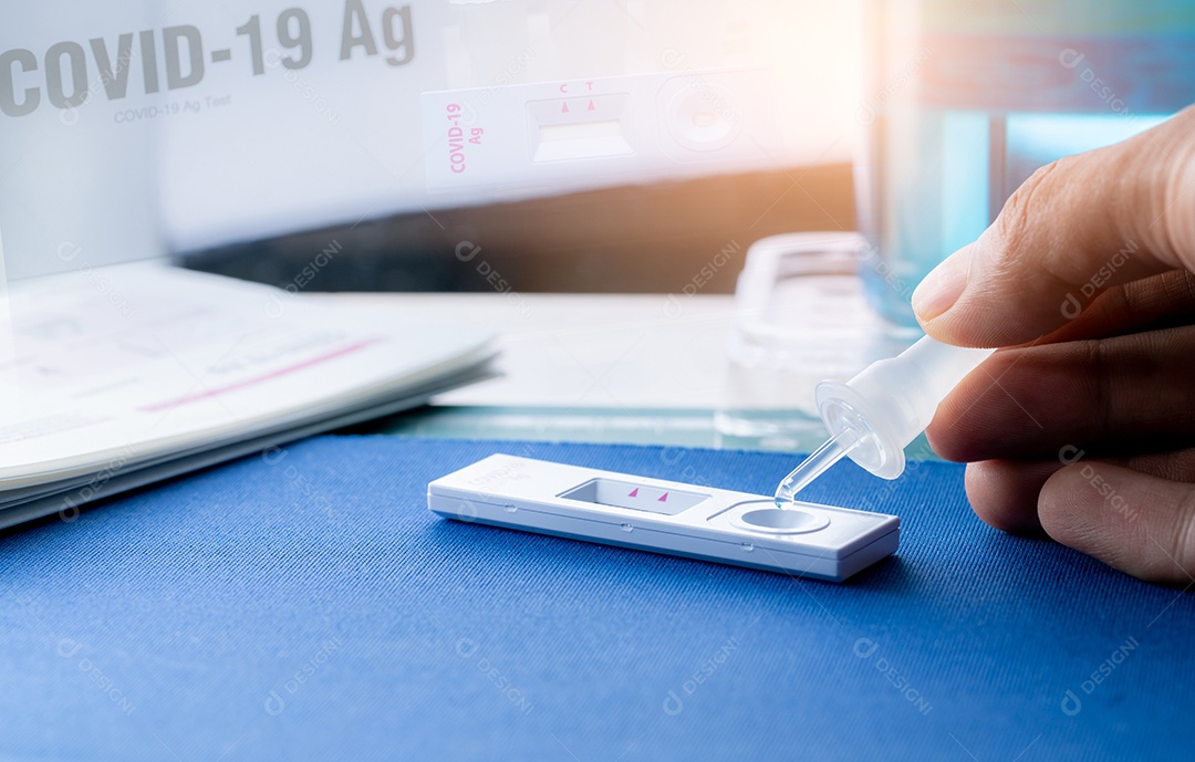 Mão segurando o tubo de amostra e gotas no dispositivo de teste do autoteste do antígeno covid 19. Kit de teste de antígeno para detecção