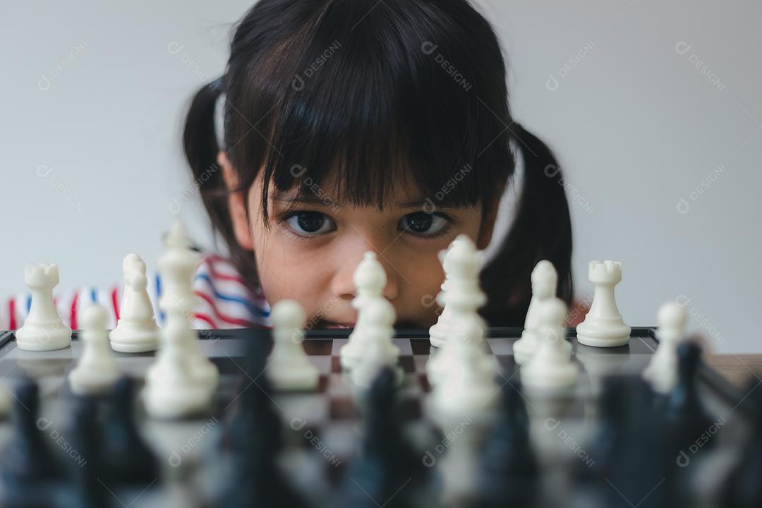 Menina asiática jogando xadrez em casa. um jogo de xadrez