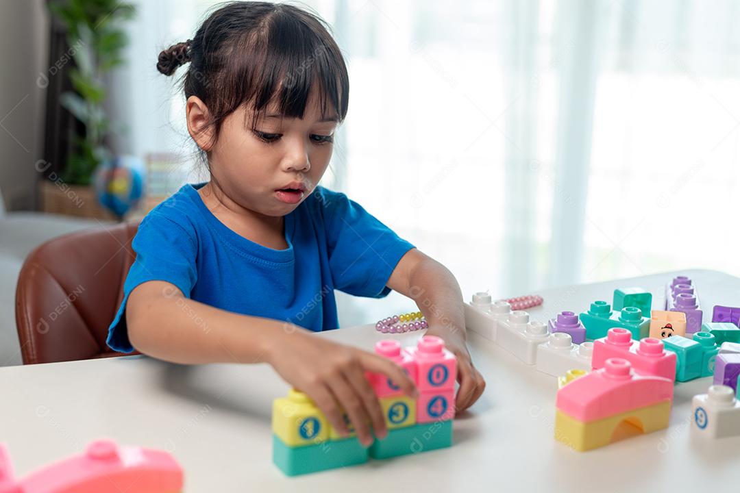 Adorável menina jogando blocos de brinquedo em uma sala iluminada