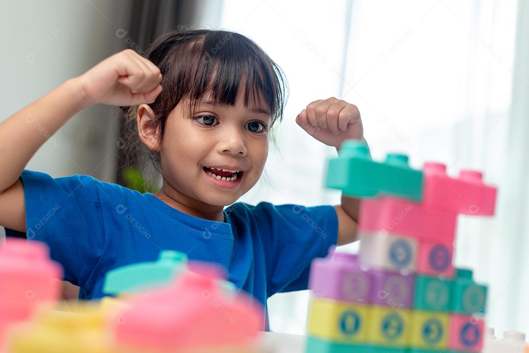 Adorável menina jogando blocos de brinquedo em uma sala iluminada