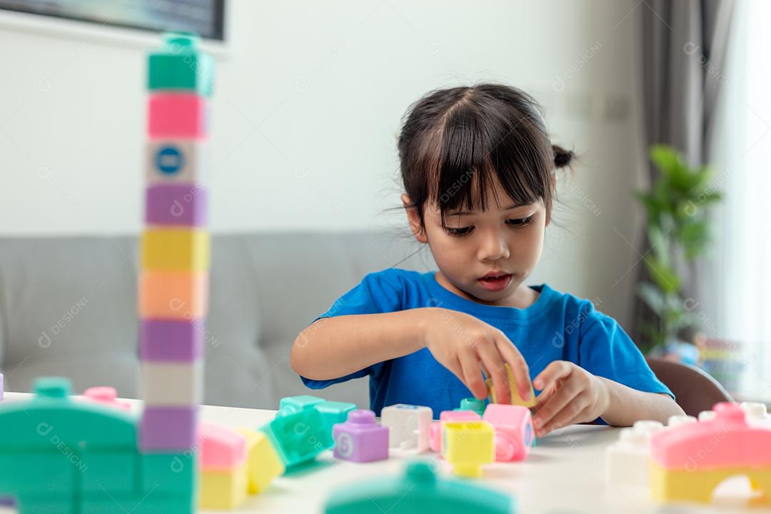 Adorável menina jogando blocos de brinquedo em uma sala iluminada