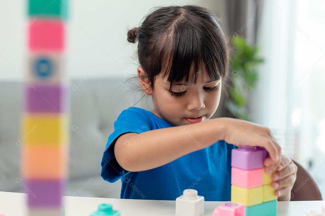 Adorável menina jogando blocos de brinquedo em uma sala iluminada