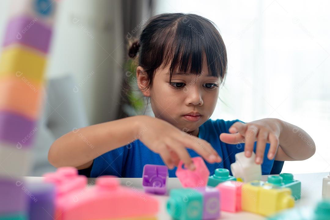 Adorável menina jogando blocos de brinquedo em uma sala iluminada