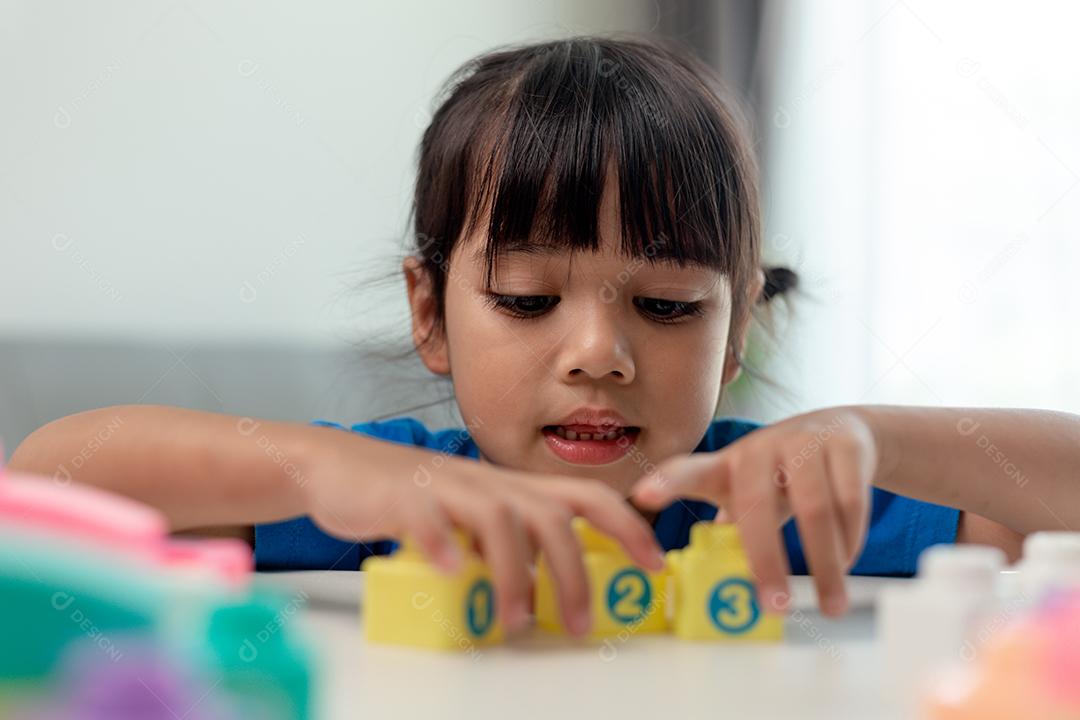 Adorável menina jogando blocos de brinquedo em uma sala iluminada
