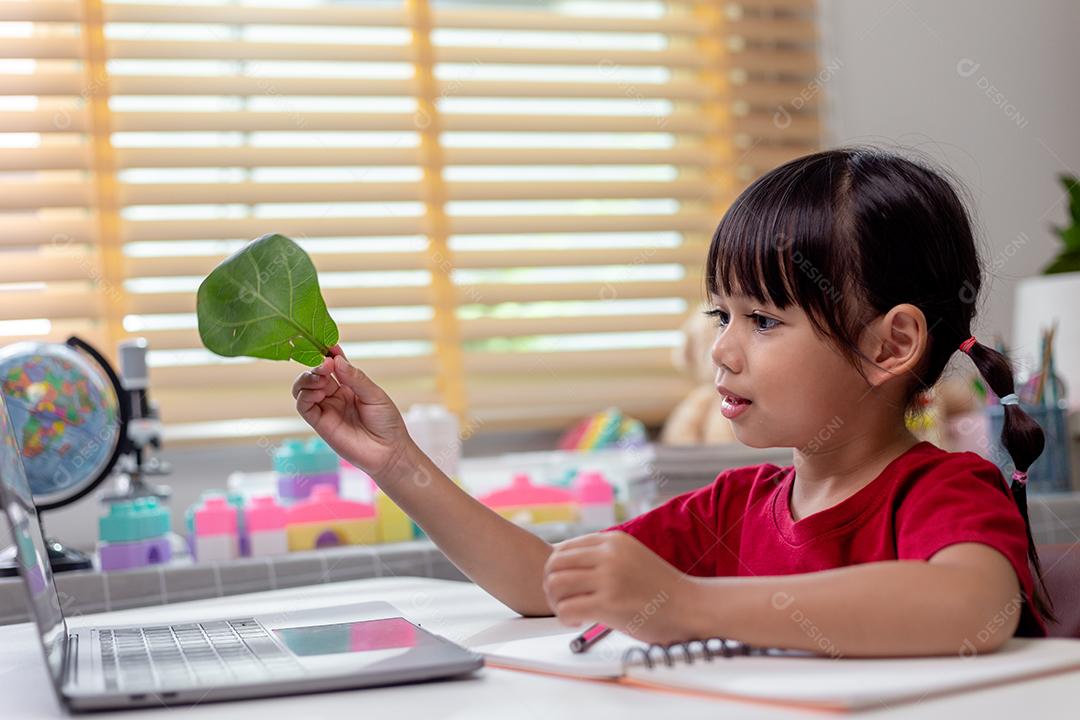 Tempo de aprendizado. Aluna interessada no fone de ouvido, sente-se na mesa de casa, assista à aula de vídeo educacional. Menina curiosa em idade escolar pensa na pergunta do professor, selecione a resposta correta na tela do laptop