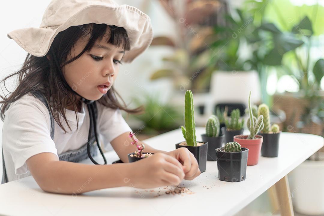 Menina asiática está plantando plantas em casa, conceito de atividade de aprendizado de crescimento de plantas para uma criança pré-escolar e educação infantil para a árvore na natureza