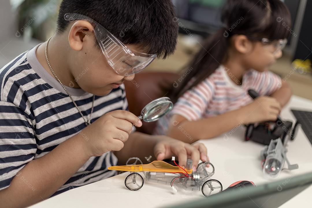 duas crianças asiáticas se divertindo aprendendo codificação juntas, aprendendo remotamente em casa, ciência STEM, educação escolar em casa, distanciamento social divertido, isolamento, novo conceito normal