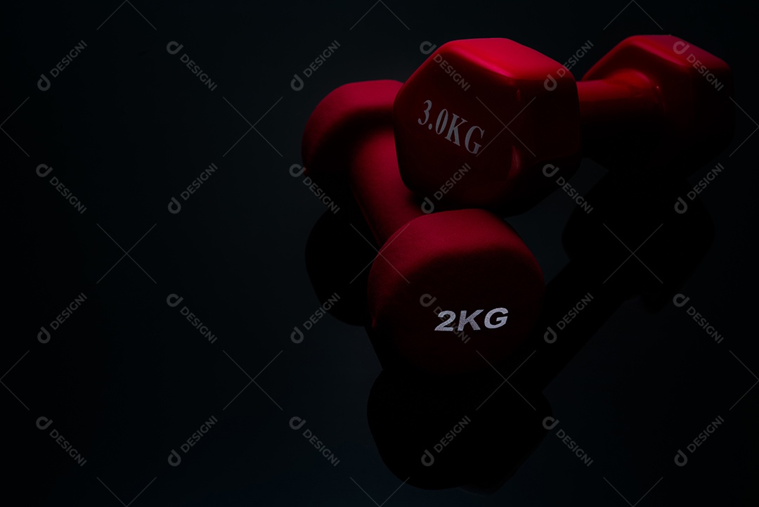Halteres rosa vermelhos e escuros isolados no fundo preto. halteres de 2,3kg. Equipamento de musculação. Acessórios de treino de musculação